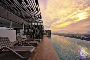 A rooftop pool area with lounge chairs and a cityscape view during sunset. - THE HORIZON IPOH BY 40 WINKS (Ipoh)