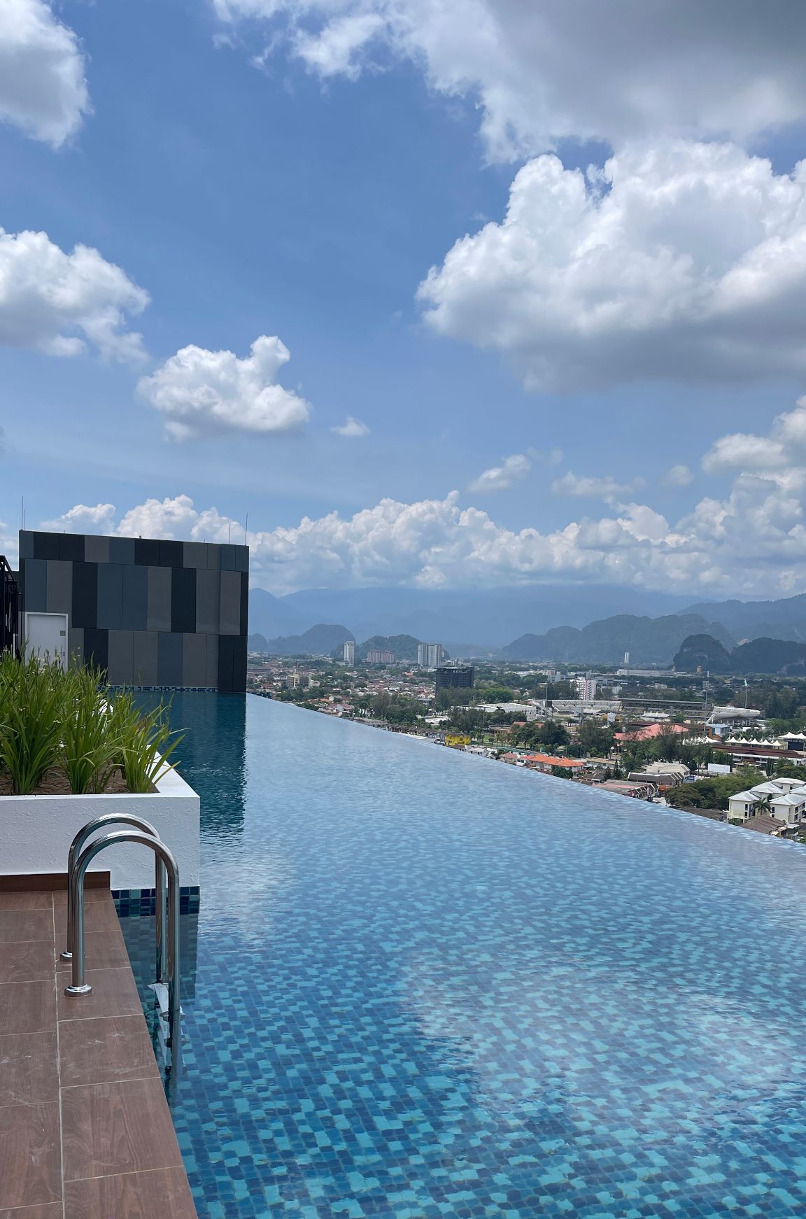 Une piscine à débordement offrant une vue sur le paysage urbain et les montagnes en arrière-plan.