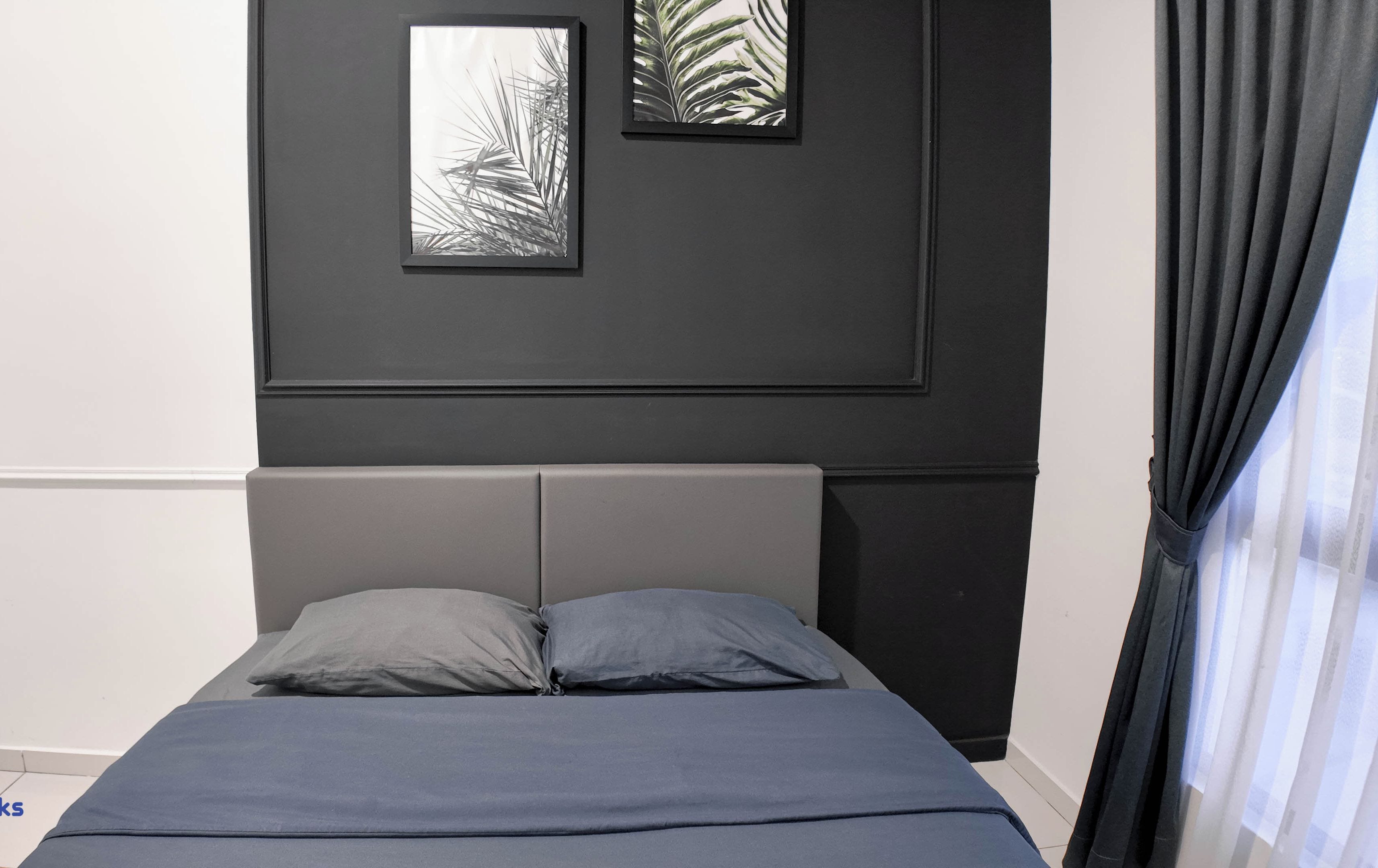 Quarto com cama, duas almofadas, cabeceira e dois quadros na parede.