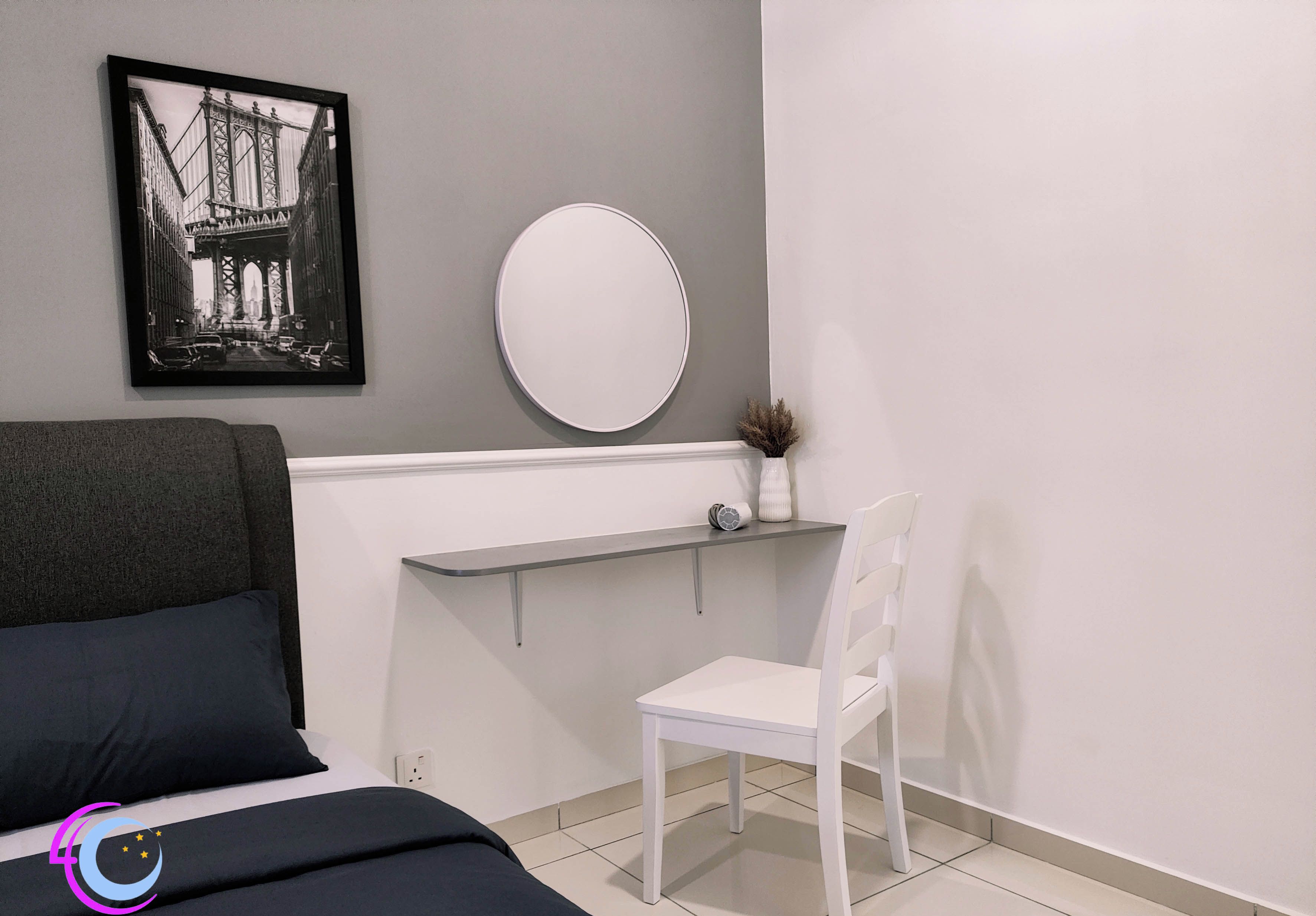 A bedroom with a bed, a desk, a chair, a mirror, and a framed picture on the wall.