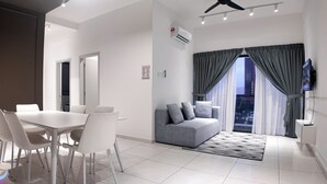 Una sala de estar moderna con comedor, sofá gris y televisor.