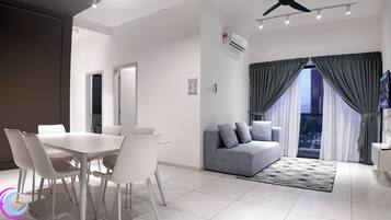 A modern living room with a dining area, grey sofa, and a TV.