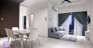 Ein modernes Wohnzimmer mit Essbereich, grauem Sofa und Fernseher.