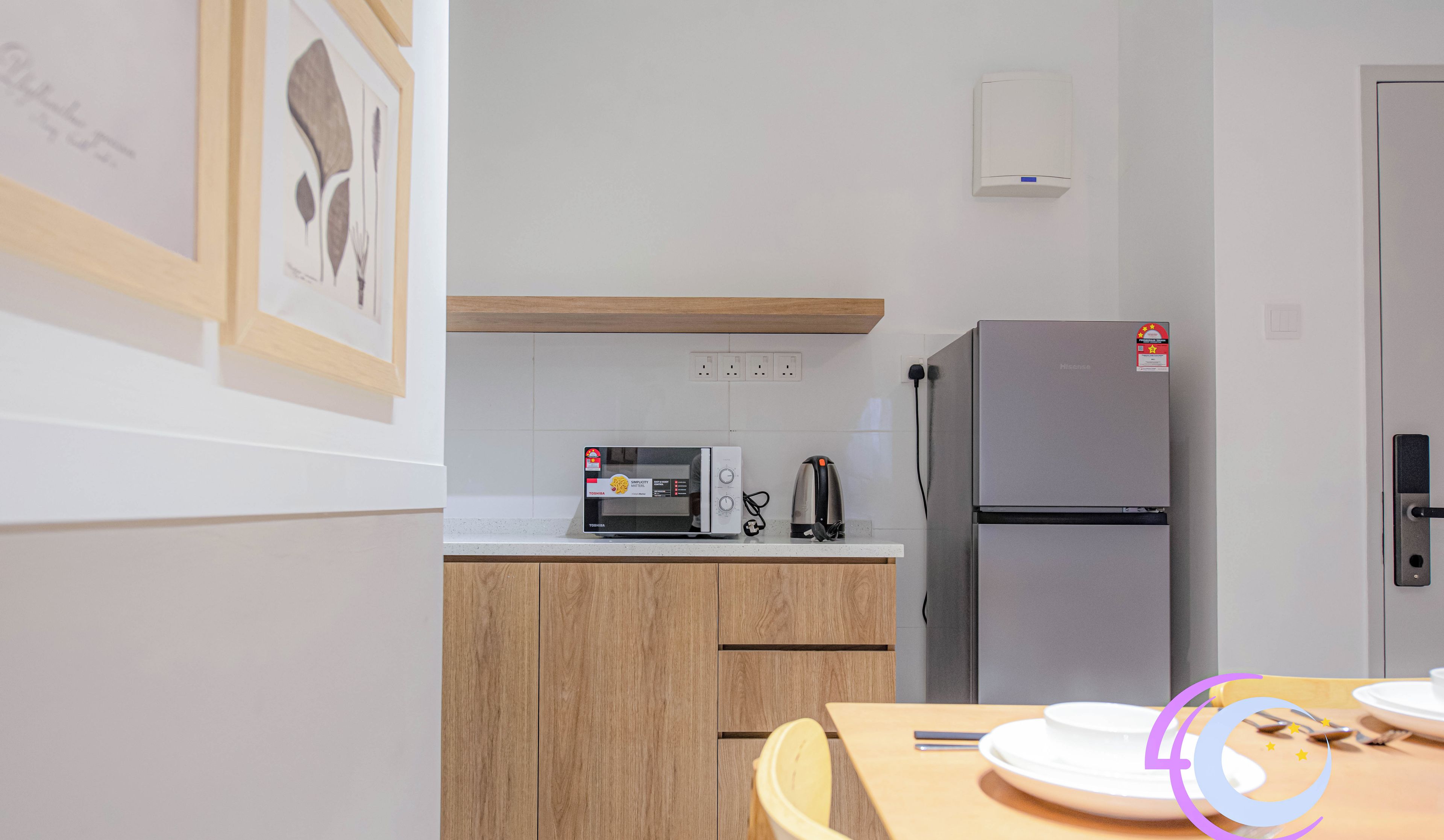 A modern kitchen with wooden cabinets, a microwave, a kettle, and a refrigerator.