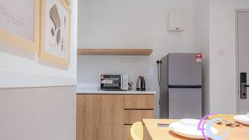 A modern kitchen with wooden cabinets, a microwave, a kettle, and a refrigerator.