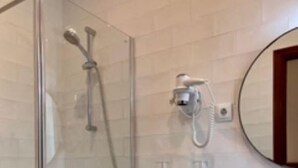 Ein Badezimmer mit Duschkabine, Toilette und Waschbecken mit Spiegel darüber.