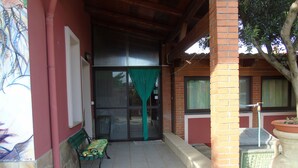 A covered outdoor area with a bench, a potted plant, and a tiled floor. - Casa Da Pina B&B (Cabras)