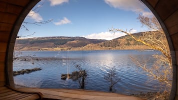 A circular window with a view of a lake, surrounded by wooden walls.