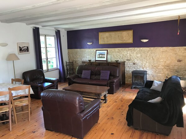 Una sala de estar con pared de piedra, chimenea y un ventanal con cortinas.