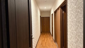 Un couloir avec des portes en bois et des murs à motifs, qui mène à une pièce dont le sol est en bois.
