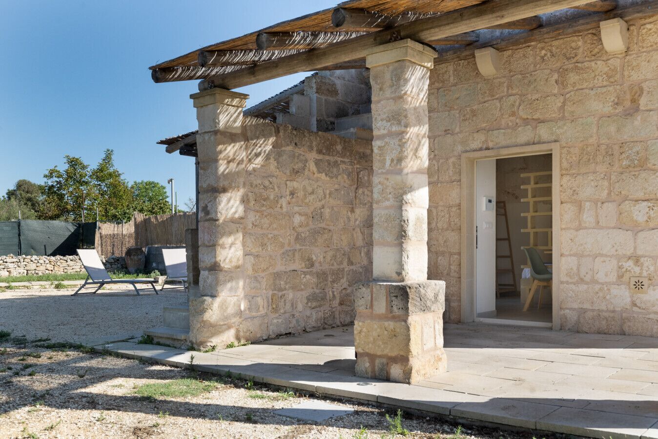Un edificio in pietra con tetto in legno, una porta e una panchina all'esterno.