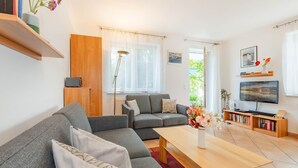 Uma sala de estar moderna com um sofá cinzento, uma mesa de centro de madeira e um aparador com livros.