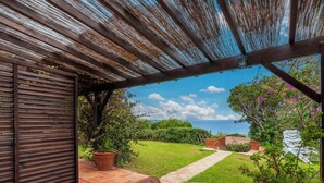 A covered patio with a table and chairs, a view of the sea, and a garden with potted plants. - Villa 19 by Interhome (Bonifacio)