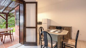 A dining area with a table and chairs, a kitchen area with appliances, and a sliding glass door leading to an outdoor patio. - Villa 19 by Interhome (Bonifacio)