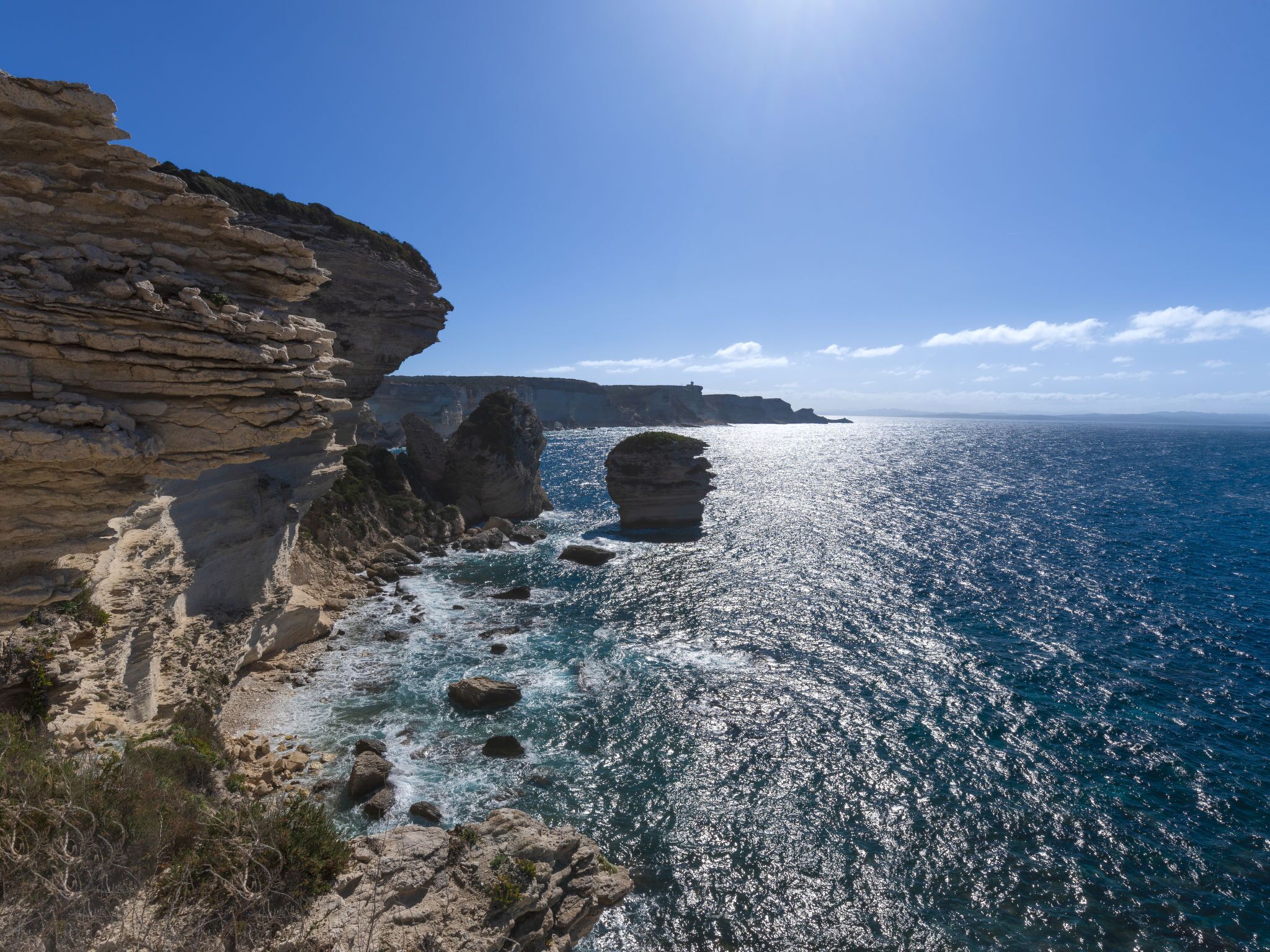 A coastal landscape with rocky cliffs and a clear blue sea.