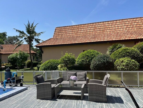 A patio area with wicker furniture, a small pool, and a building with a tiled roof.