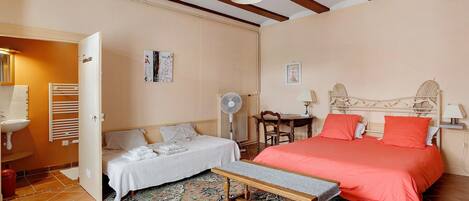 A bedroom with a bed, bedside table, chair, and a small table with a lamp.