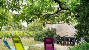 Un jardin doté d’un espace extérieur aménagé avec une table, des chaises et un fauteuil avec un dossier.