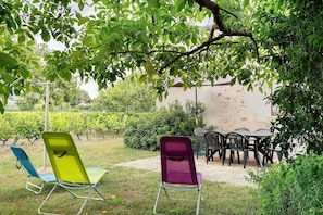 A garden with outdoor seating, including a table and chairs, and a chair with a backrest.