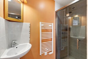 A bathroom with a white sink, a mirror, a towel rack, and a glass shower enclosure.