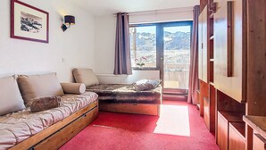 Una habitación con una cama de madera, un sofá, una mesita y una ventana con vistas a la montaña.