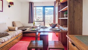 Una habitación acogedora con una cama, una mesa de comedor para dos personas y vistas a un paisaje montañoso a través de una ventana.