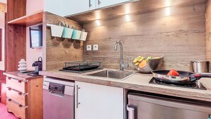 Una cocina moderna con armarios blancos, un lavamanos de acero inoxidable y un lavavajillas integrado.
