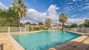 A rectangular swimming pool with clear blue water, surrounded by a white fence, and palm trees in the background. - Les Parcs de Gassin by Interhome (Gassin)