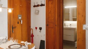 Une pièce avec une porte en bois, une table mise pour le repas et un miroir qui reflète une salle de bain.
