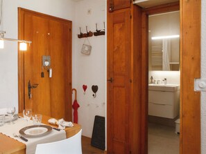 Ein Zimmer mit Holztür, einem gedecktem Tisch und einem Spiegel, der ein Badezimmer reflektiert.