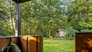 A wooden deck with a table set for a meal, surrounded by a lush garden and a wooden structure in the background. - "Cornel" - 300m from the sea by Interhome (Strøby)
