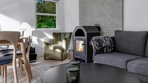 A modern living room with a fireplace, a sofa, a chair, and a dining table. - "Cornel" - 300m from the sea by Interhome (Strøby)