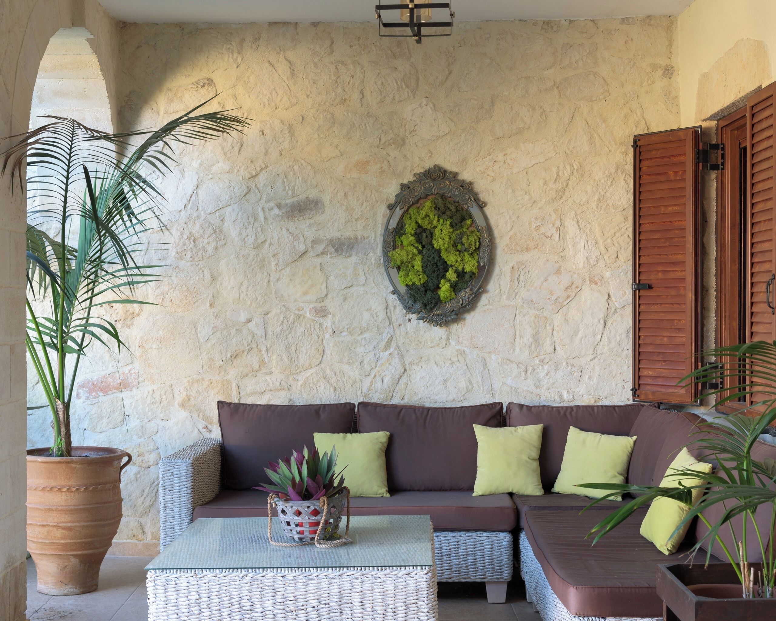 A cozy living area with a stone wall, a sofa with cushions, a coffee table, and a potted plant.