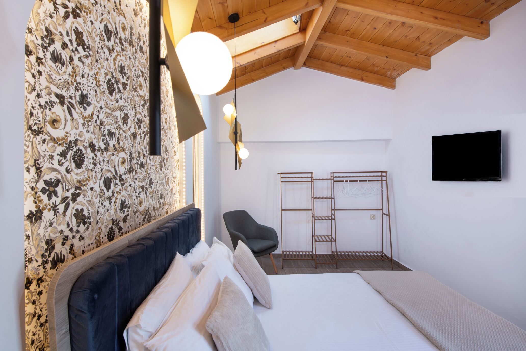 Ein Schlafzimmer mit Bett, Sessel, Fernseher und Kleiderschrank.