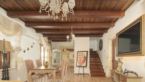 A dining area with a wooden table and chairs, a chandelier, and a staircase leading to another level. - Nicole Villa (Apokoronas)
