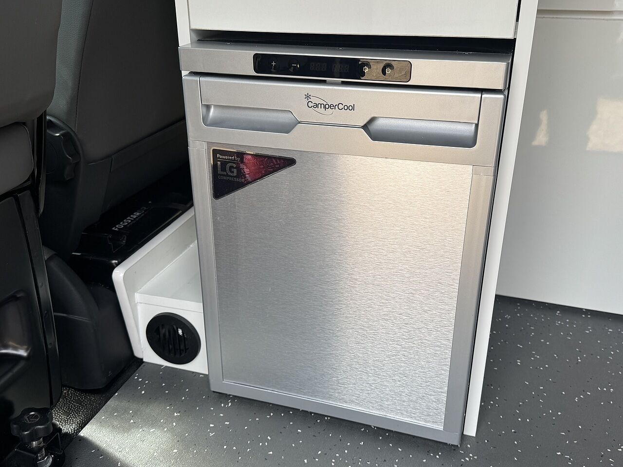 A compact, silver portable refrigerator with a digital display, branded 'CamperCool', and a small compartment below it.