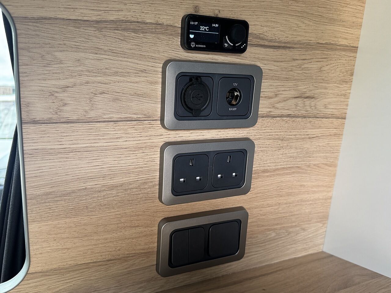 Een houten paneel met een thermostaat, een 12V stopcontact, twee USB-poorten en een schakelaar.