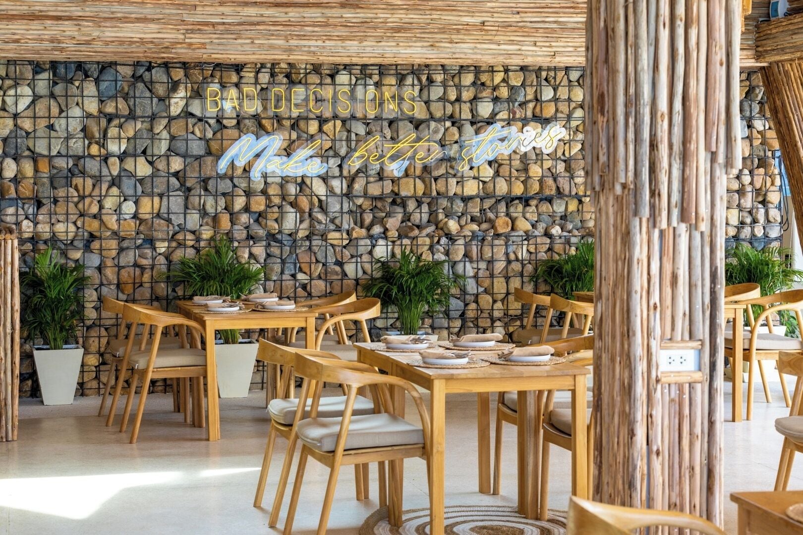 Ein Restaurant mit Steinwand, Holzmöbeln und einem Neon-Schild.