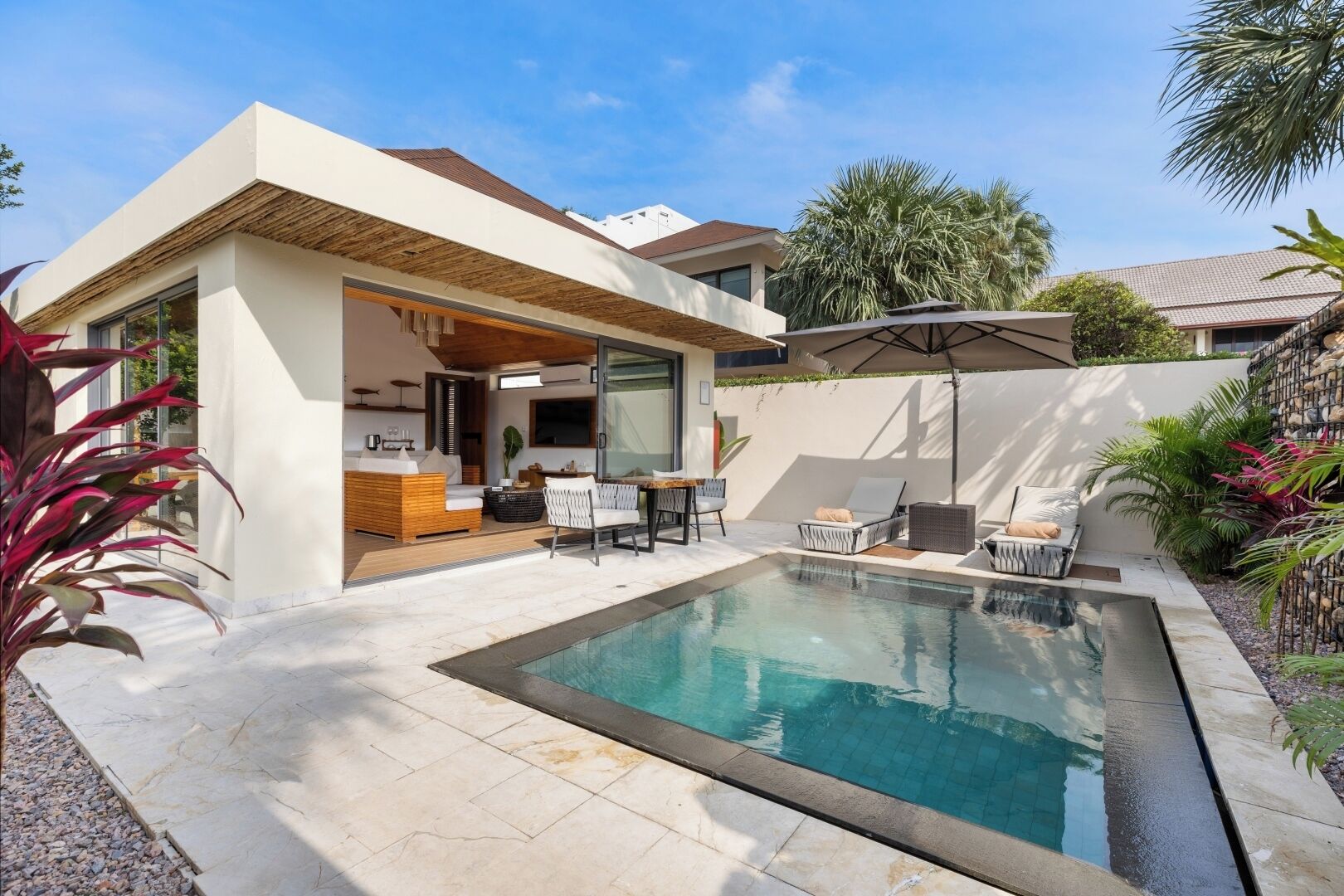 A modern house with a swimming pool, outdoor seating, and a patio area.