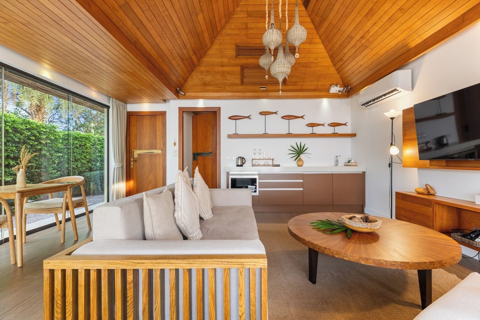 A modern interior with a wooden ceiling, a sofa, a dining table, and a kitchen area.