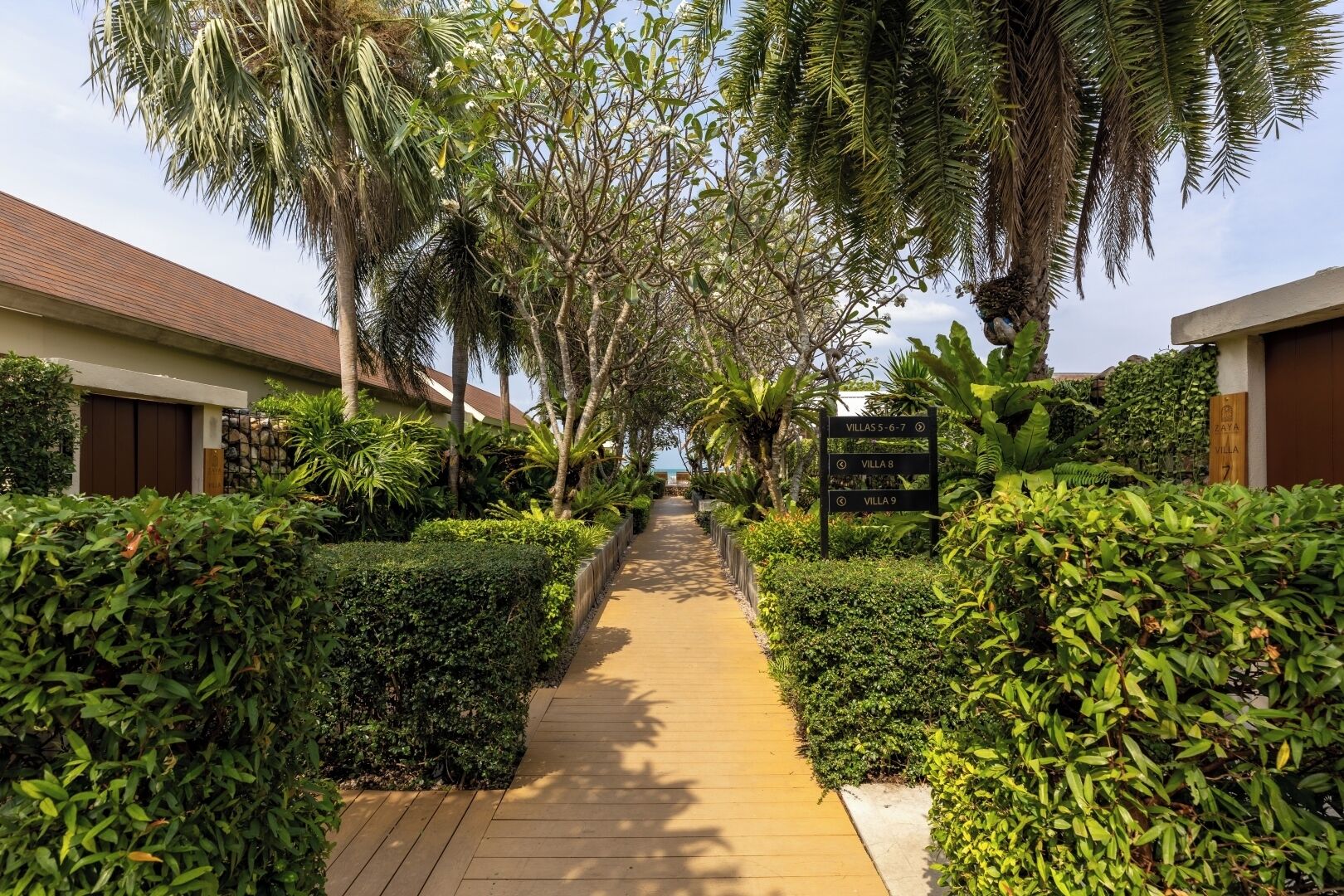 A pathway lined with lush greenery and palm trees leading to villas numbered 5-7, 8, and 9.