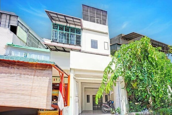 A multi-story residential building with a garage, a motorcycle, and a tree in the foreground.