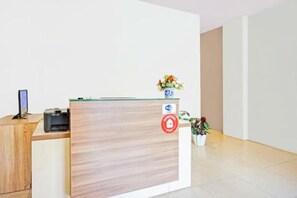 Un comptoir d’accueil avec un ordinateur, une imprimante et un vase rempli de fleurs.