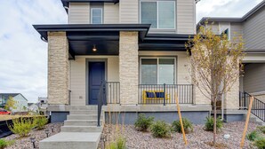 A two-story house with a stone facade, a dark front door, and a small porch with a bench. - Great for Families! Newly Built Home in Aurora (Aurora)