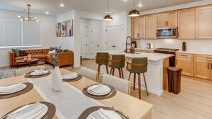 A modern kitchen with wooden cabinets, a central island, and bar stools. - Great for Families! Newly Built Home in Aurora (Aurora)