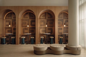 A modern interior with wooden walls, arched niches, round tables, and stools.