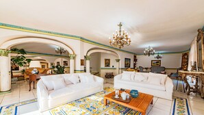 Ein geräumiges Wohnzimmer mit zwei weißen Sofas, einem Holztisch und aufwändig gestalteten Fliesen.