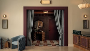 A room with a checkered floor, a fireplace, a mirror, and a sign indicating an elevator. - Pool, Restaurant, Creative Space, Terrace | Minutes from Zilker & Lady Bird (Austin)