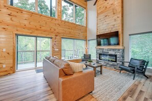 Ein geräumiges Wohnzimmer mit einer großen Holzbalkendecke, einem Kamin aus Stein und einem Ledersofa.