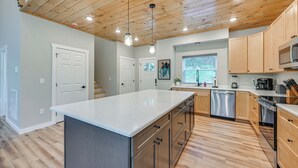 Une cuisine moderne avec des meubles en bois, des appareils en acier inoxydable et un grand îlot central.